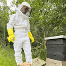  Apicultor com Macacão SR PREMIUM branco e Luvas SR CROSS amarelo 100% antiferroadas abrindo caixa colmeia de abelhas com ferramenta saca quadros com formão durante manejo no apiário